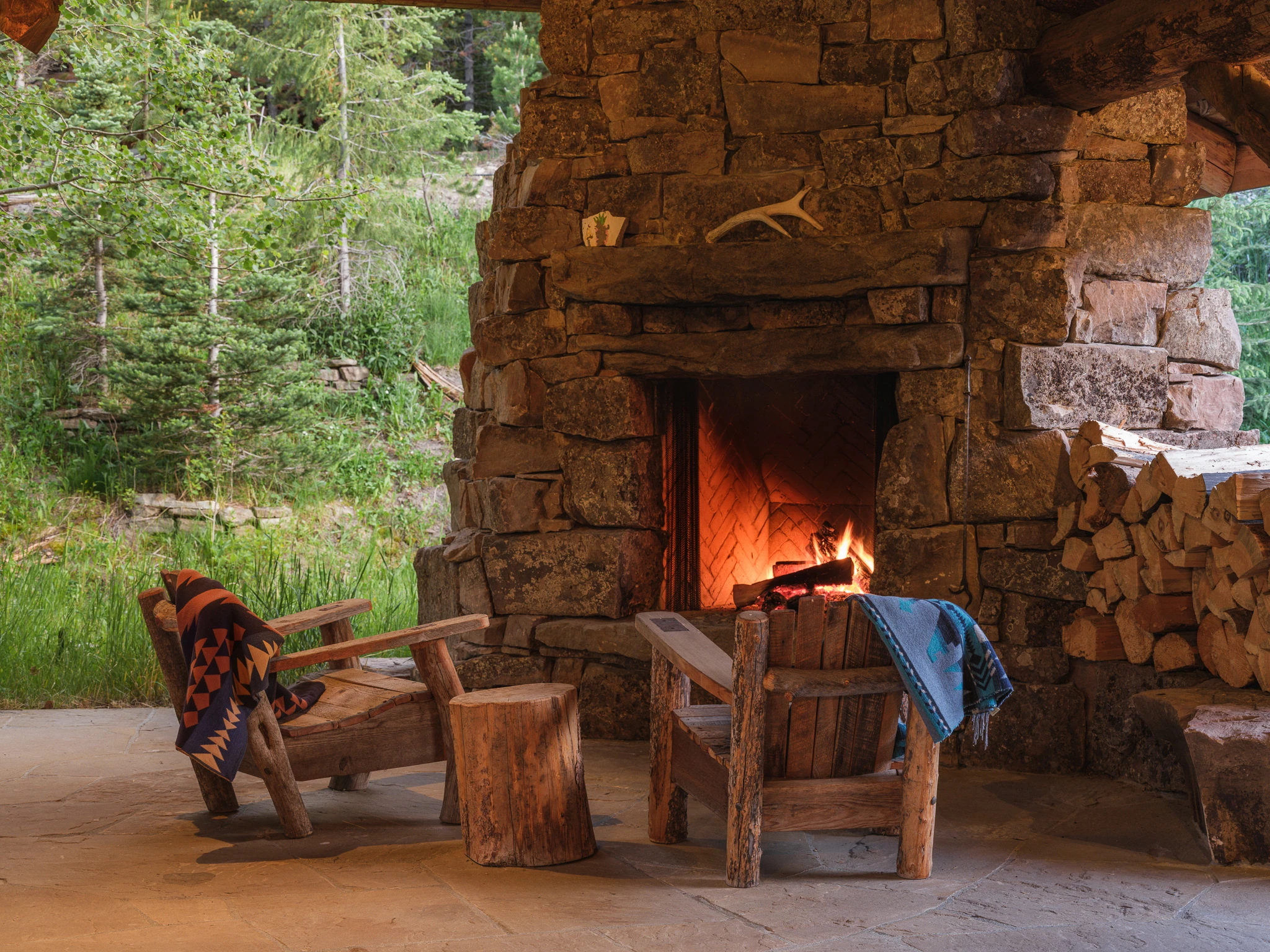 Outdoor stone fireplace and log chairs — architectural photography Big Sky Montana, Club Ridge